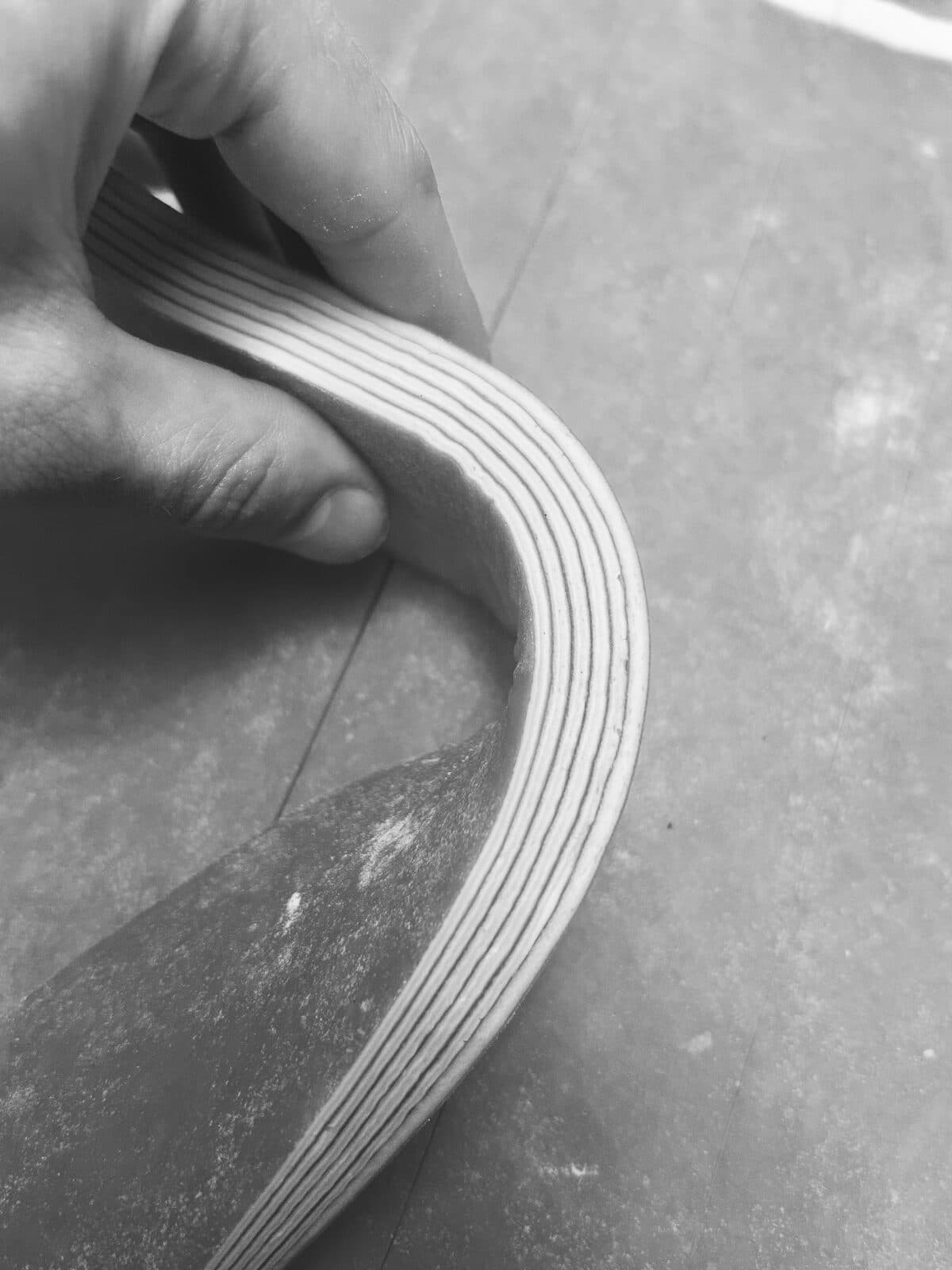 Main pliant une bande de pâte feuilletée laissant apparaître ses couches