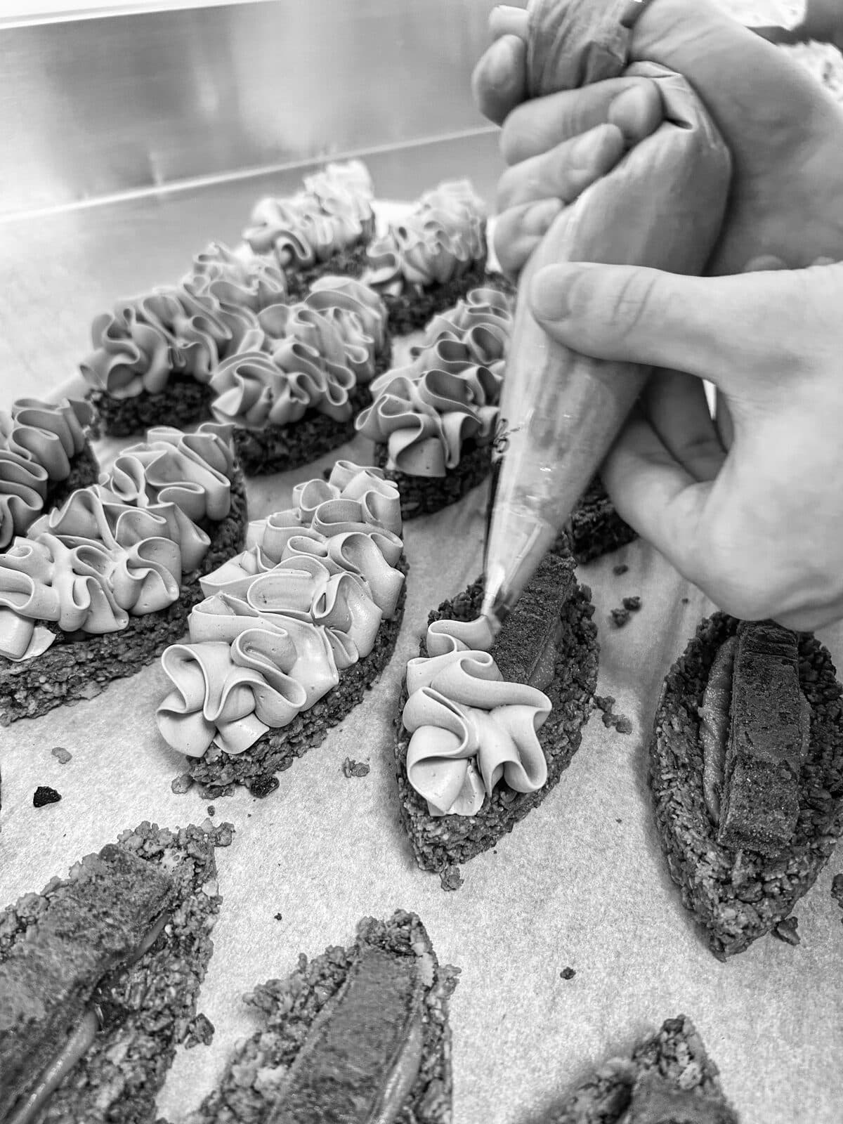Mains pochant une crème à la poche à douille sur des fonds de pâtisserie
